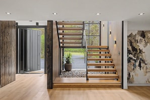 A modern interior with a wooden staircase, a potted plant, and a textured wall. - New Modern Creekfront Mansion with Indoor Pool and Sauna by Camelback (Tannersville)
