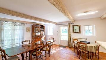 Een eetkamer met een houten tafel en stoelen, een buffetkast en een raam met gordijnen.
