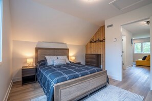 Een slaapkamer met een bed, een houten hoofdbord, nachtkastjes en een raam.