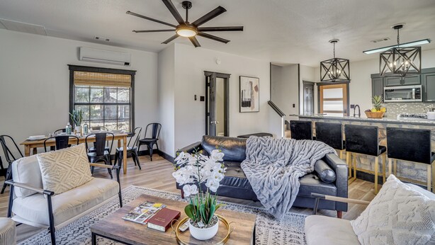 A modern living room with a sofa, chairs, a coffee table, and a dining area with a table and chairs. - Pool Access, Walk to Water! Possum Kingdom Cabin (Graford)