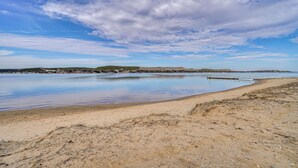 A beach with a calm water body, sandy shore, and distant hills. - Pool Access, Walk to Water! Possum Kingdom Cabin (Graford)