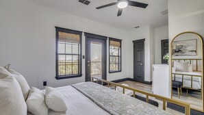 A bedroom with a bed, a ceiling fan, and a view of the outdoors through a window. - Pool Access, Walk to Water! Possum Kingdom Cabin (Graford)