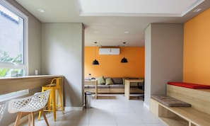 Un espace de vie moderne comprenant un canapé, un coin repas avec une table et des chaises, une poubelle et une fenêtre donnant sur un paysage agréable.