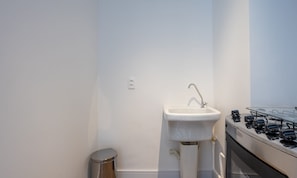 A small, modern bathroom with a white sink, a stainless steel trash bin, and a gas stove. - Apt w/ Balcony 350m From Shopping Ecg1308 (São Paulo)