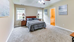 A bedroom with a bed, nightstands, a ceiling fan, and a view of the bathroom. - 6 Mi to Fort Benning: Quiet Home w/ Patio & Yard (Columbus)
