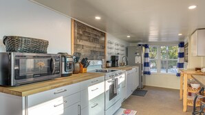 A modern kitchen with white cabinets, a wooden countertop, a built-in oven, and a microwave. - Sun & Sand in St Pete! Family Home w/ Tiki Bar (St. Petersburg)