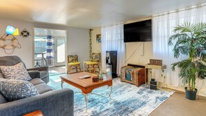 A living room with a sofa, coffee table, and chairs, a television, and a potted plant. - Sun & Sand in St Pete! Family Home w/ Tiki Bar (St. Petersburg)