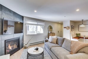 Ein modernes Wohnzimmer mit Kamin, einer Couch, einem Couchtisch und einem Essbereich mit Tisch und Stühlen.