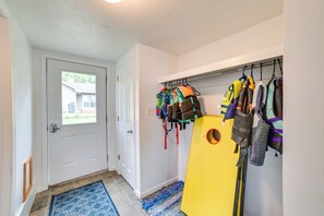 Ein Flur mit einer zur Garage führenden Tür, einem gelben Kajak und verschiedenen Rettungswesten, die an der Wand hängen.