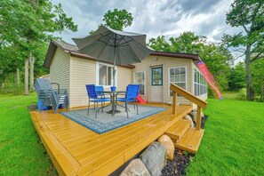 Eine Holzterrasse mit Tisch und Stühlen, ein überdachter Patio-Bereich und eine kleine Rutsche.