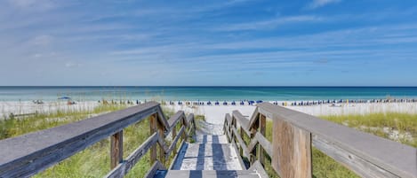 A wooden boardwalk leading to a beach with clear skies.