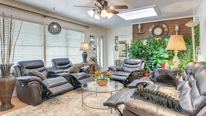 A living room with leather recliners, a glass coffee table, and a large plant. - Shop, Dine & Explore: Home 3 Mi to NRG Stadium (Houston)