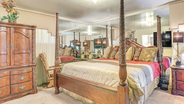 A spacious bedroom with a large bed, a wooden dresser, and a mirror reflecting the room. - Shop, Dine & Explore: Home 3 Mi to NRG Stadium (Houston)