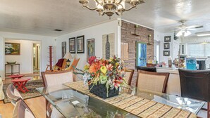 A dining area with a glass table, cushioned chairs, and a floral centerpiece. - Shop, Dine & Explore: Home 3 Mi to NRG Stadium (Houston)