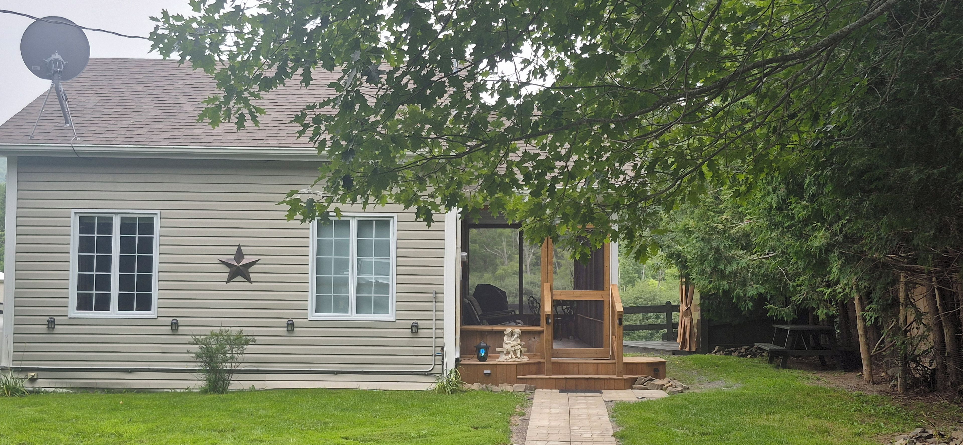 Une maison dotée d’un porche abrité, d’une antenne parabolique et d’un petit jardin.