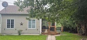 A house with a covered porch, a satellite dish, and a small garden area.