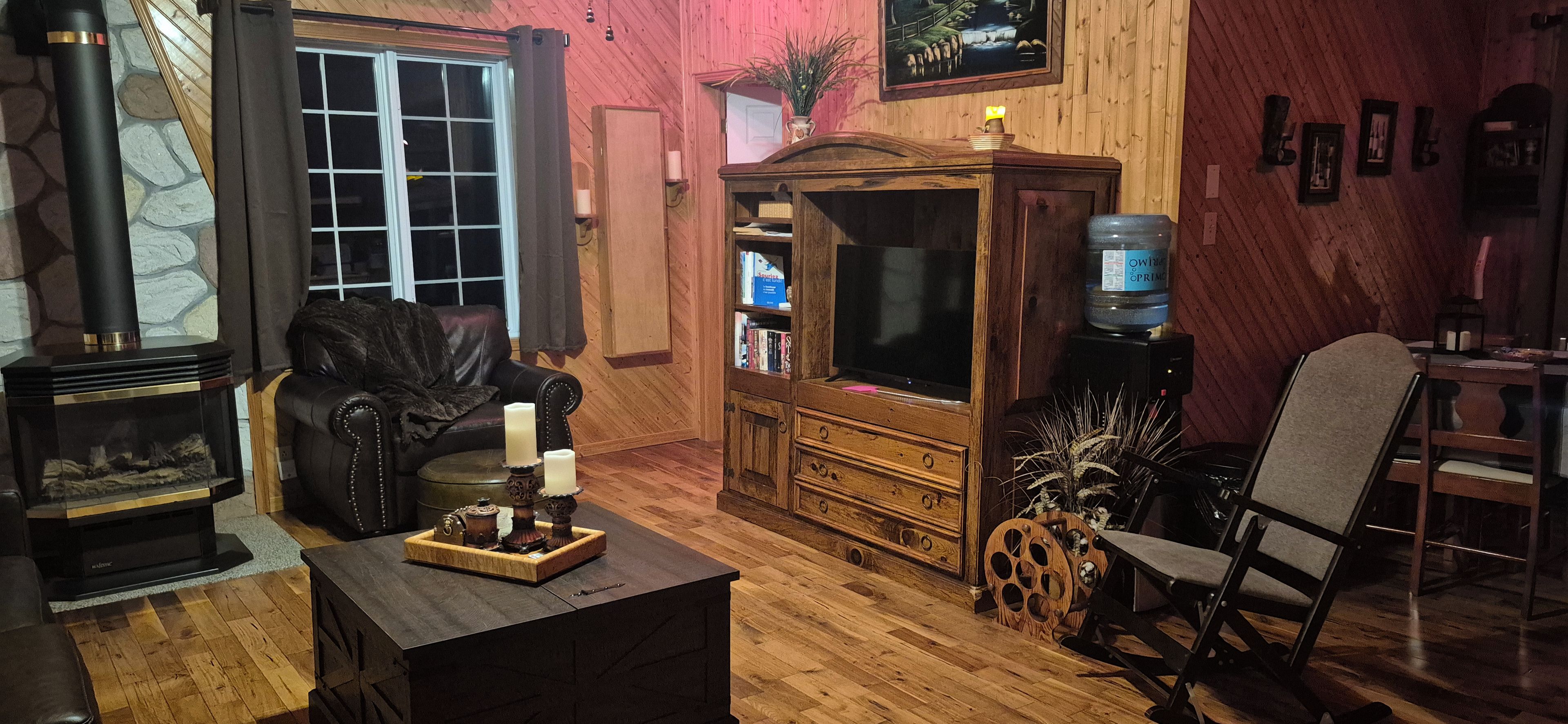 A cozy living room with a fireplace, leather sofa, wooden cabinet, and a television.