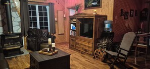 A cozy living room with a fireplace, leather sofa, wooden cabinet, and a television.