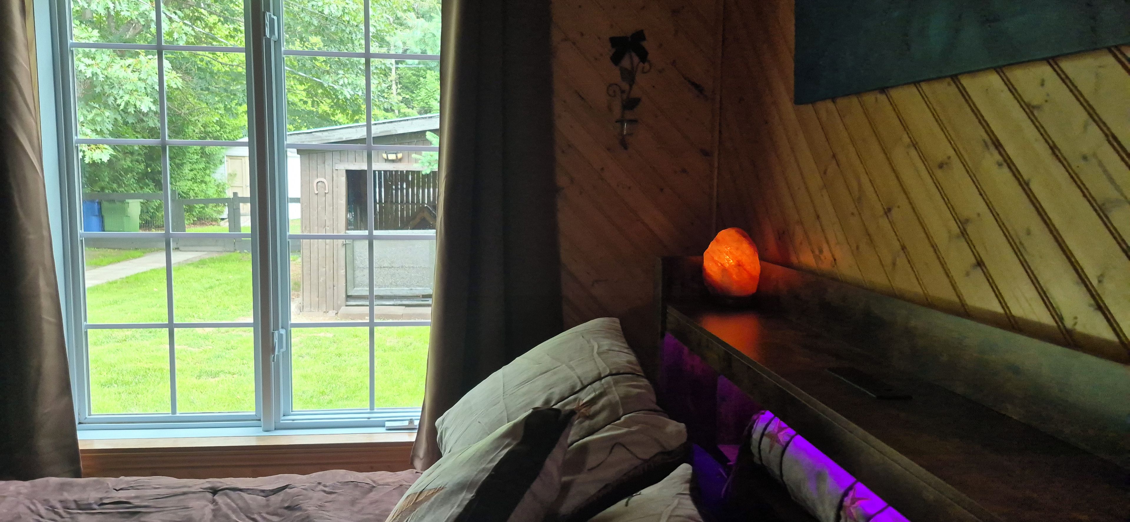 Une pièce avec un lit, une fenêtre et un mur en bois.