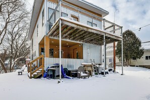 En toetagers bygning med balkon, træterrasse og en overdækket udendørs opholdsplads.