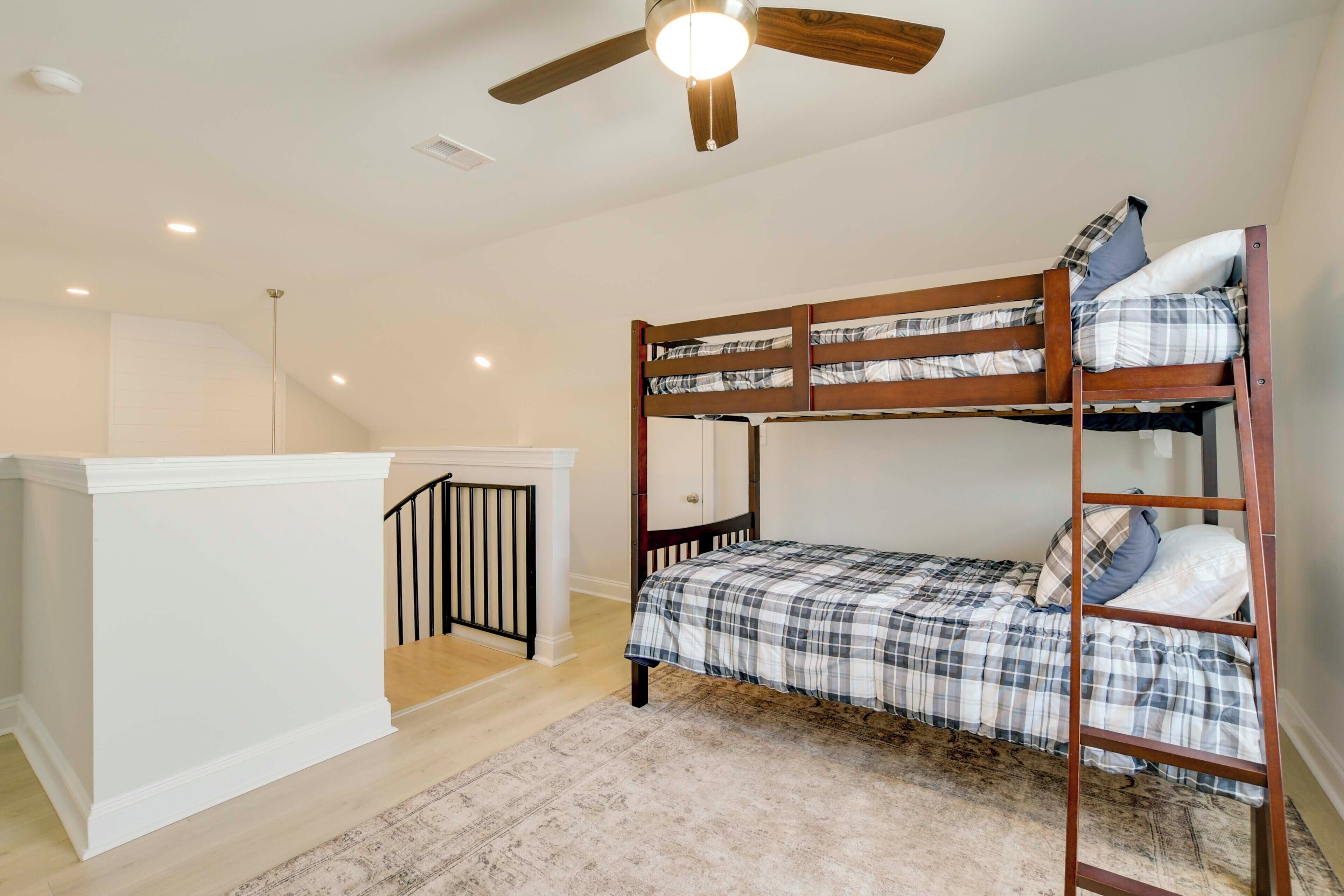 A bunk bed room with a ceiling fan, a small staircase, and a white cabinet.