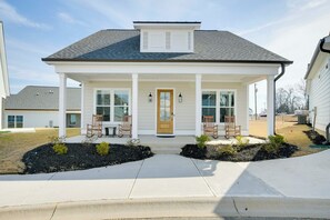 Une maison à deux étages avec un porche à l’avant, deux fenêtres et une porte.