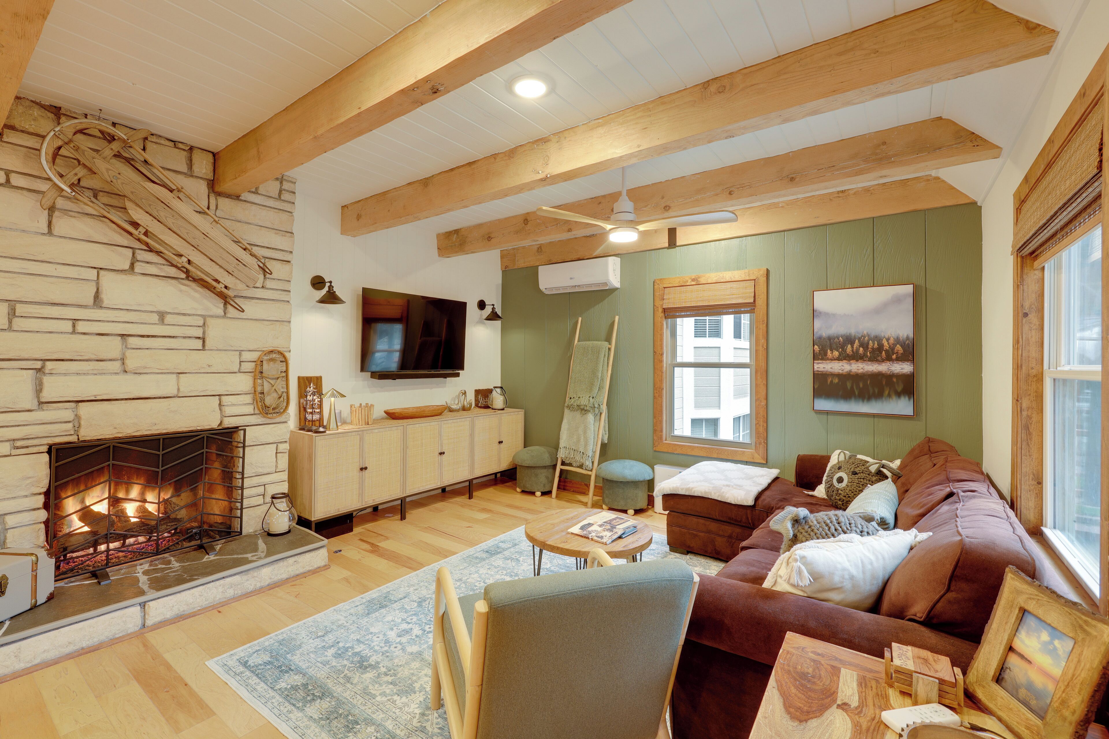 Una sala de estar acogedora con chimenea, vigas de madera, televisor y sofá.