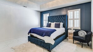 Un dormitorio con una cama grande, una mesita de noche, una silla y una araña.