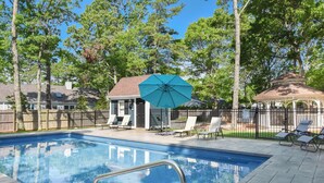 Piscina com espreguiçadeiras e um gazebo em um quintal.