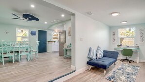 A spacious living area with a blue sofa, dining table, and chairs. There is a kitchen in the background with a refrigerator and a window. - Sarasota Home: Near Beaches & Downtown! (Sarasota)