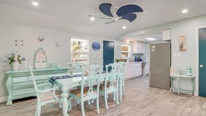 A dining area with a light green table and matching chairs, a ceiling fan, and a kitchen in the background. - Sarasota Home: Near Beaches & Downtown! (Sarasota)