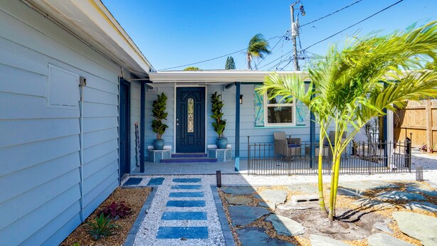 A residential house with a blue door, potted plants, and a stone pathway leading to the entrance. - Sarasota Home: Near Beaches & Downtown! (Sarasota)