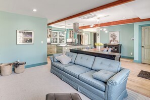 Ein modernes Wohnzimmer mit einem blauen Sofa, einer Küchenzeile und Holzbalken an der Decke.
