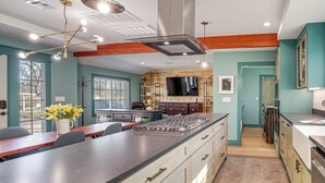 Una cocina moderna con una isla central, vigas de madera y un ventanal grande.