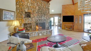 Ein gemütliches Wohnzimmer mit Kamin aus Stein, Ledermöbeln und Holzboden.