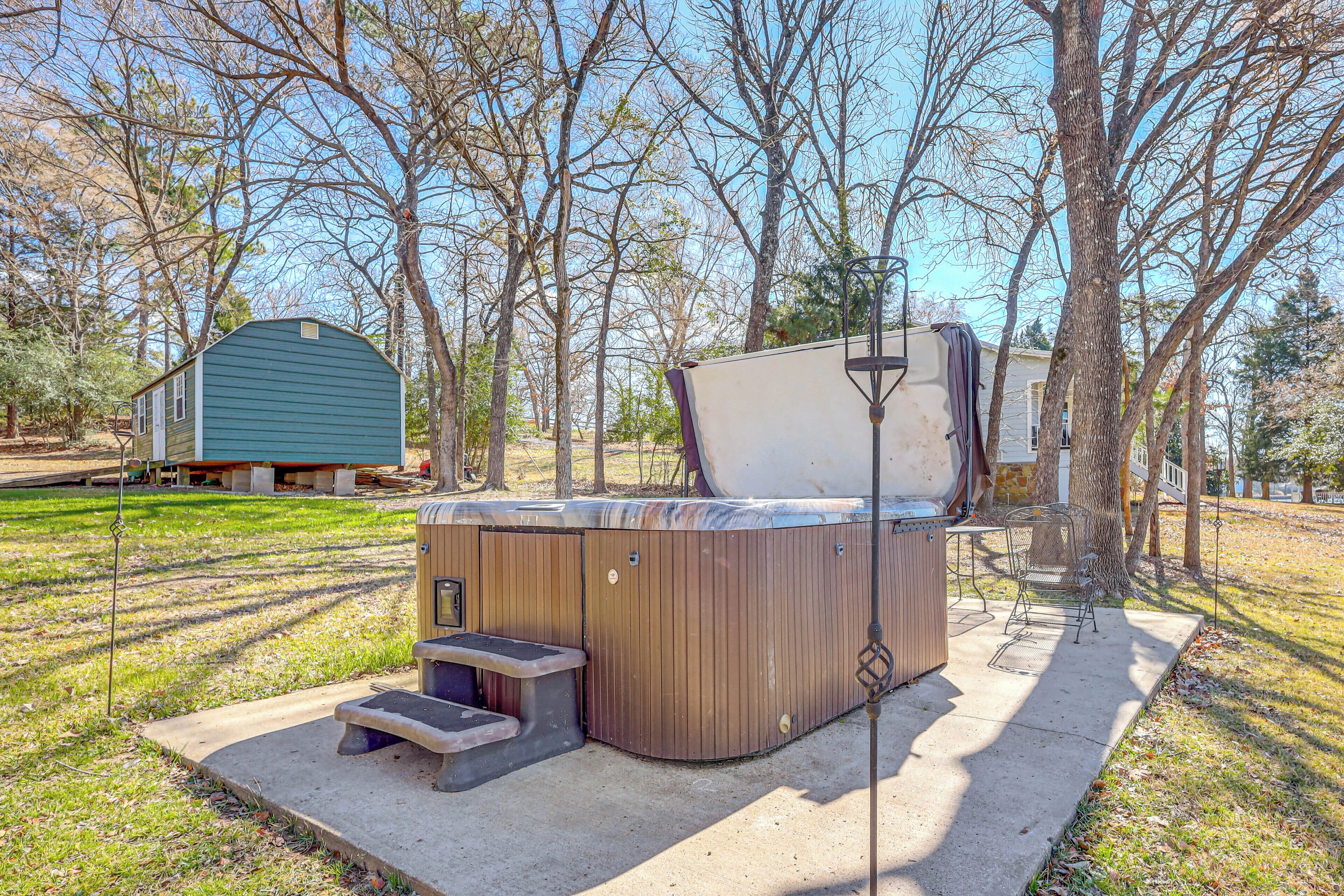 Ein Whirlpool mit Treppen und Tisch, umgeben von Bäumen und einer Gartenhütte auf einem Grundstück.