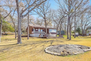 A cabin with a porch, surrounded by trees and a circular garden area.