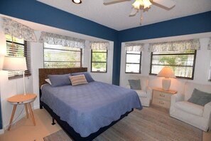 A bedroom with a bed, bedside tables, a chair, and a ceiling fan. - Pelican Paradise- Pets Welcome! (Englewood)