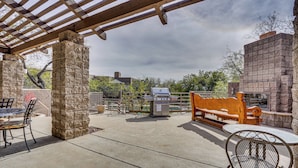 Eine Terrasse im Freien mit Grill, Sitzgelegenheiten und Steinsäulen.