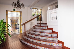 A staircase with ornate railings and patterned tiles, leading to a door marked "SALIDA DE EMERGENCIA". - Charming Studio with Balcony + Pool on Santo Domingo square, old city (Cartagena de Indias)