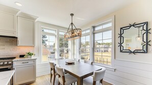 A kitchen with a large dining table, white cabinets, a stove, and a view through large windows. - Family Friendly! Canal-Front Gem in Bethany Beach (Bethany Beach)