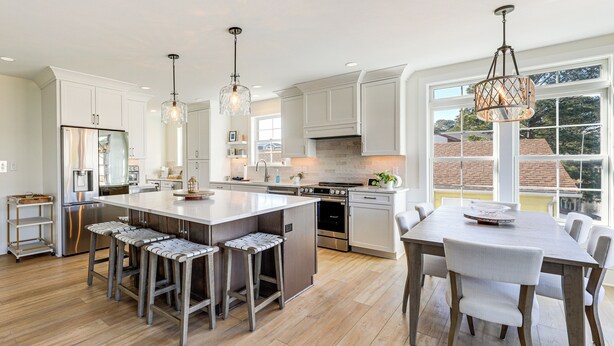 A modern kitchen with a central island, bar stools, a dining table with chairs, and pendant lighting. - Family Friendly! Canal-Front Gem in Bethany Beach (Bethany Beach)