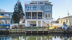 A two-story waterfront house with a balcony, a dock, and a small boat. - Family Friendly! Canal-Front Gem in Bethany Beach (Bethany Beach)