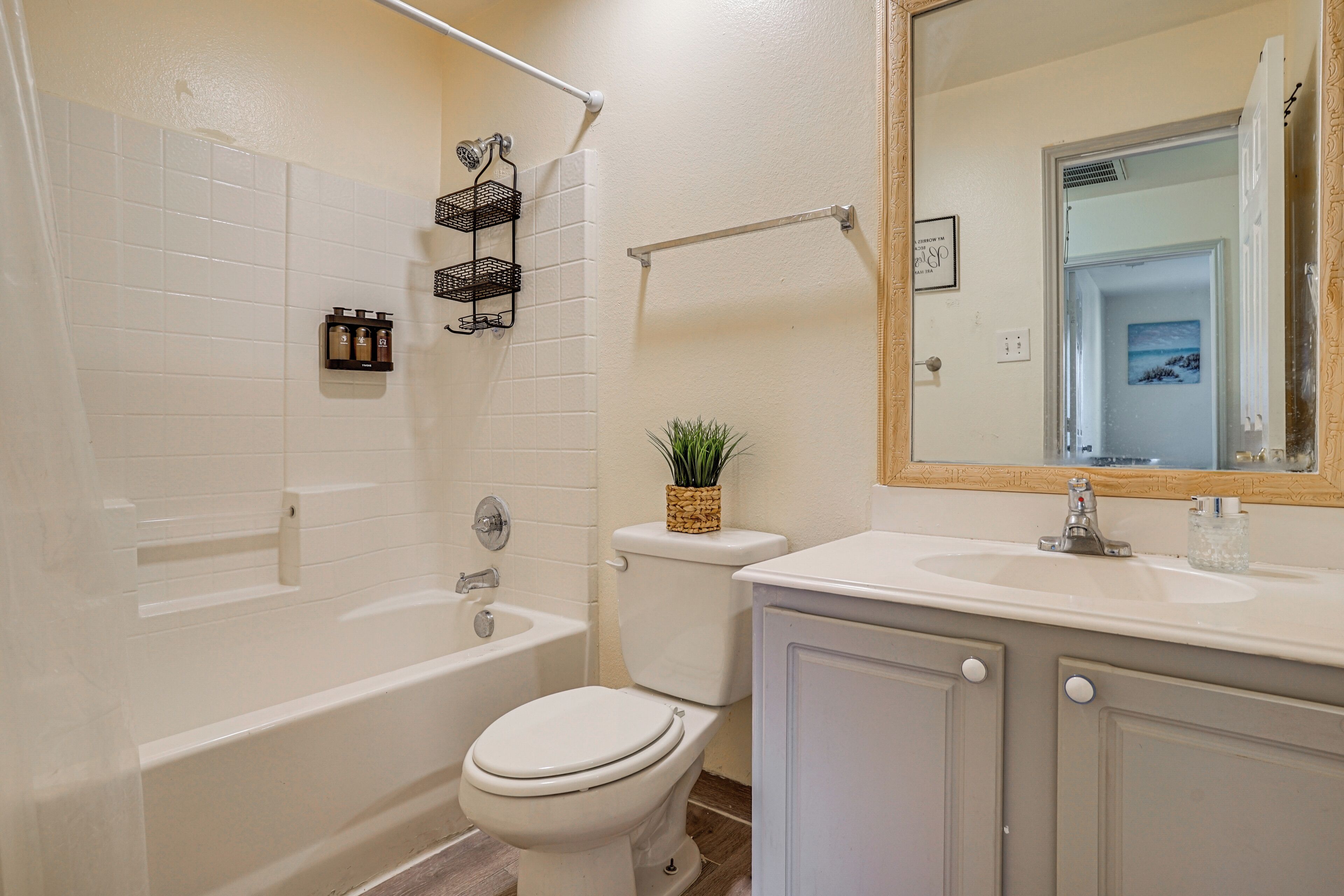 A bathroom with a bathtub, toilet, and sink. There are towel racks and a mirror above the sink.