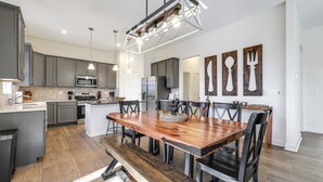 A modern kitchen with grey cabinets, a wooden dining table, and a central island. - Lake Lure Getaway w/ Hot Tub & Fire Pit! (Lake Lure)