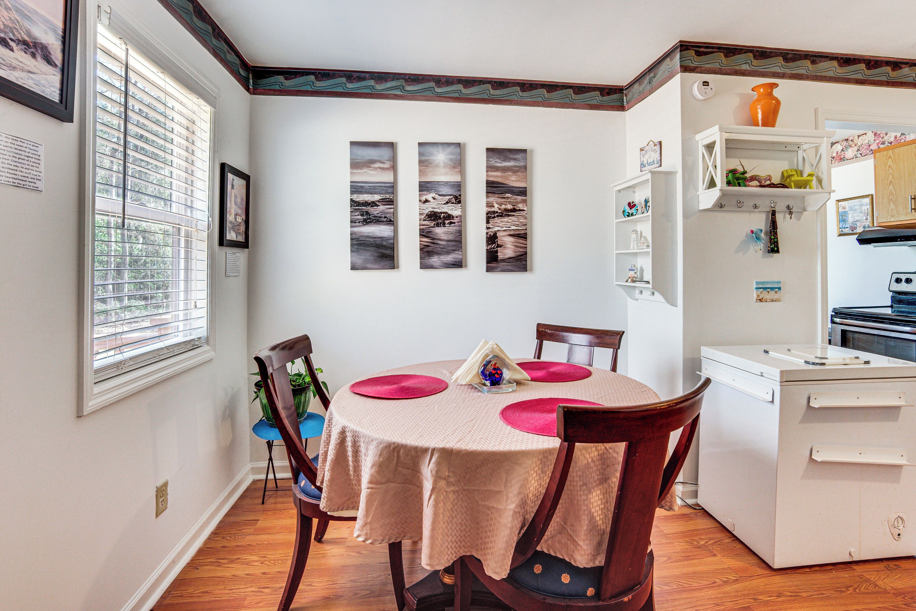 A dining area with a round table, chairs, and a white cabinet with shelves.