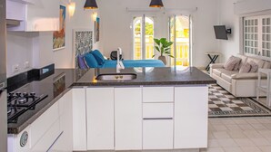 A modern kitchen with white cabinets, a central island, a stove, and pendant lighting. - Charming Colonial Studio with Balcony on Santo Domingo Square + Pool (Cartagena de Indias)