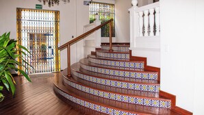 A staircase with ornate railings and patterned tiles, leading to a door marked "SALIDA DE EMERGENCIA". - Charming Colonial Studio with Balcony on Santo Domingo Square + Pool (Cartagena de Indias)