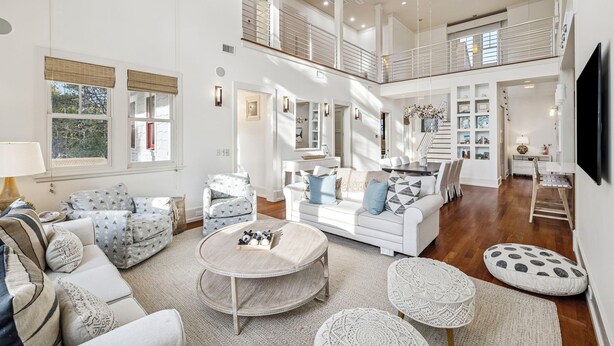 A spacious living area with a high ceiling, a staircase, and a TV mounted on the wall. - Private Beach Access | Bikes | Patio (Watersound)