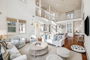 A spacious living area with a high ceiling, a staircase, and a TV mounted on the wall. - Private Beach Access | Bikes | Patio (Watersound)